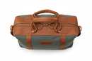 Top view close-up of zipper, brass hardware and leather handles on canvas duffel bag